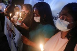Angelia Pranthaman, sister of Pannir Selvam Pranthaman, a Malaysian drug trafficker facing the death sentence, cries at a vigil for Nagaenthran Dharmalingam, another Malaysian drug trafficker who was hanged last year. She is holding a placard reading 'abolish the death penalty' and other women are holding candles.