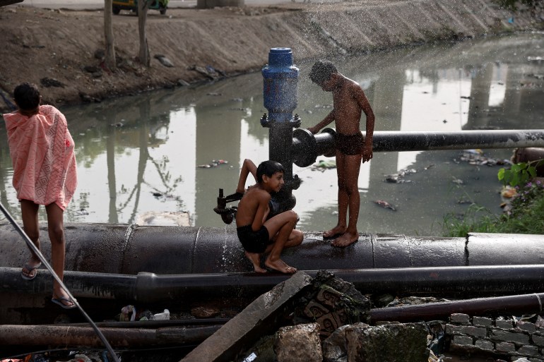 Boys cool off on a broken water pipe on a hot summer day in New Delhi, India, May 17, 2022. 