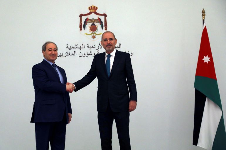 Jordan's Foreign Minister Ayman Safadi shakes hands with Syria's Foreign Minister Faisal Mekdad