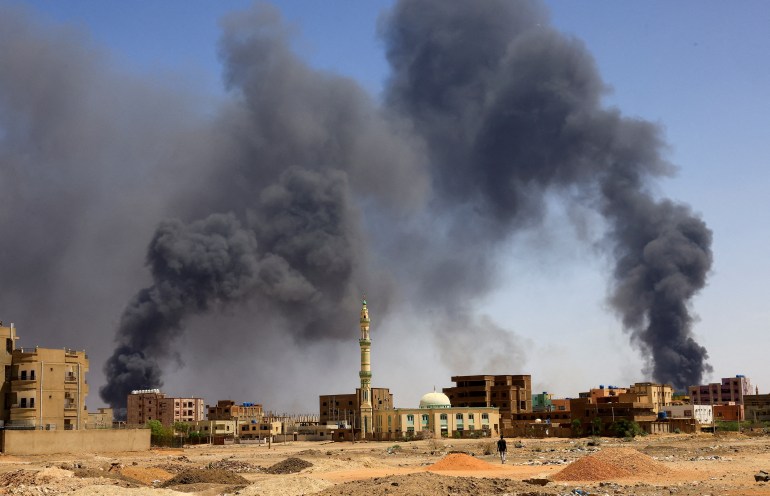 A man walks while smoke rises above buildings after aerial bombardment in Khartoum North, Sudan, May 1, 2023.