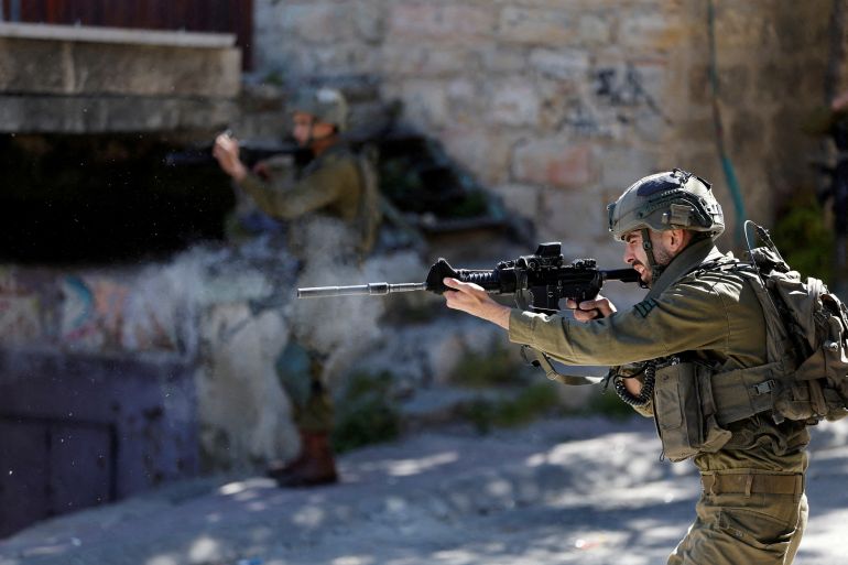 An Israeli soldier shoots rubber bullets at Palestinians in Hebron in the Israeli-occupied West Bank [