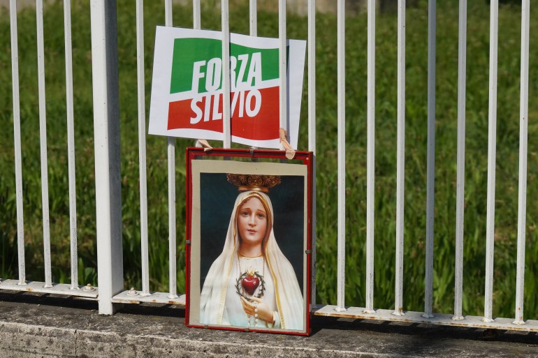 An image depicting the Virgin Mary is placed next to a Forza Italia party logo outside the 'San Raffaele' hospital where former Italian Prime Minister Silvio Berlusconi is hospitalised, in Milan