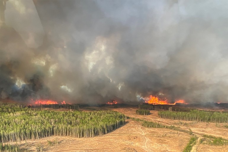 A smoke column rises from wildfire WWF023 near Fox Creek, Alberta, Canada