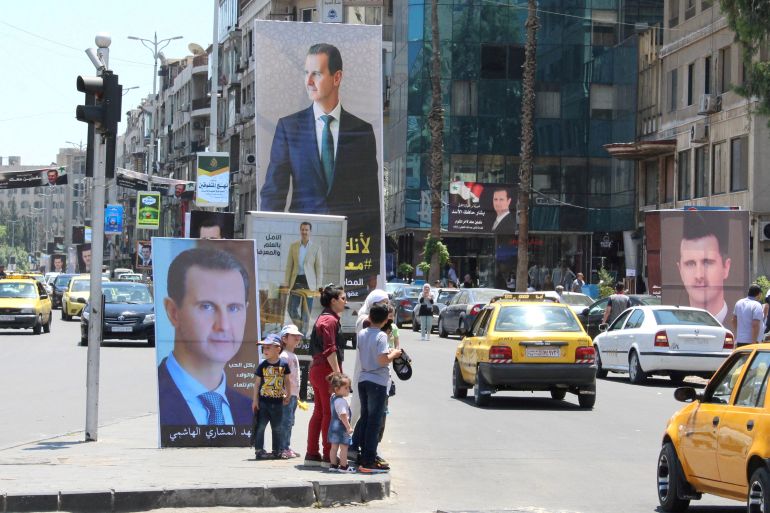 People stand near posters depicting Syria's President Bashar al-Assad, ahead of the May 26 presidential election