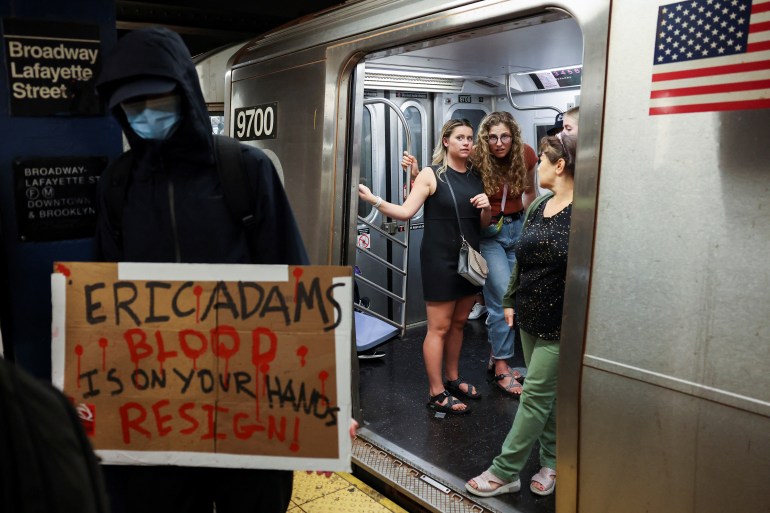 New York City subway riders look at a protest over the death of subway passenger Jordan Neely