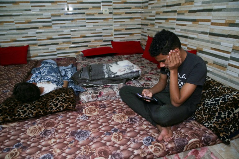 A Palestinian boy watches news on his phone at his house in Khan Younis in the southern Gaza Strip