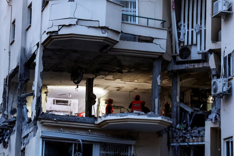 Israeli rescue personel check a damaged apartment where a rocket fired from Gaza hit, in Rehovot, Israel.