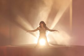 Swedish singer Loreen back lit as she performs on stage.
