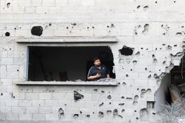 A Palestinian man stands in the window opening of the site of an Israeli air raid amid Israel-Gaza fighting in Deir al-Balah town in the central Gaza Strip.