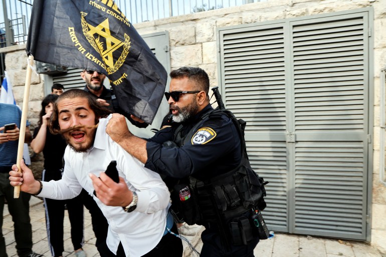A policeman pushes an Israeli man