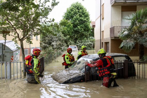 Firefighters work next to a flooded car, covered in mud, after heavy rains hit Italy's Emilia-Romagna region, in Faenza, Italy, May 18, 2023. [Claudia Greco/Reuters]