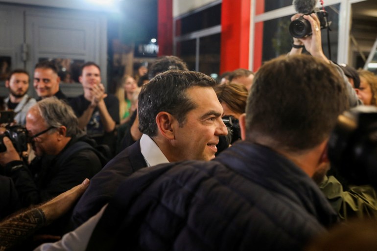 Alexis Tsipras at his party's headquarters surrounded by supporters and photographers.
