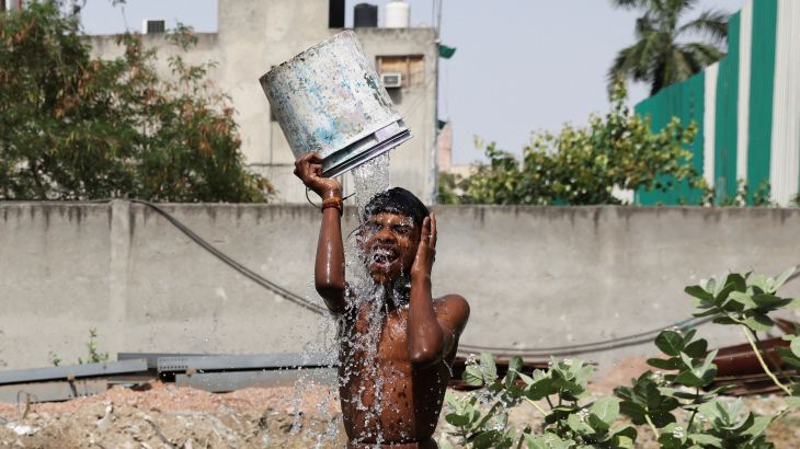 A boy bathes outside his residence on a hot summer day in New Delhi, India, May 22, 2023.