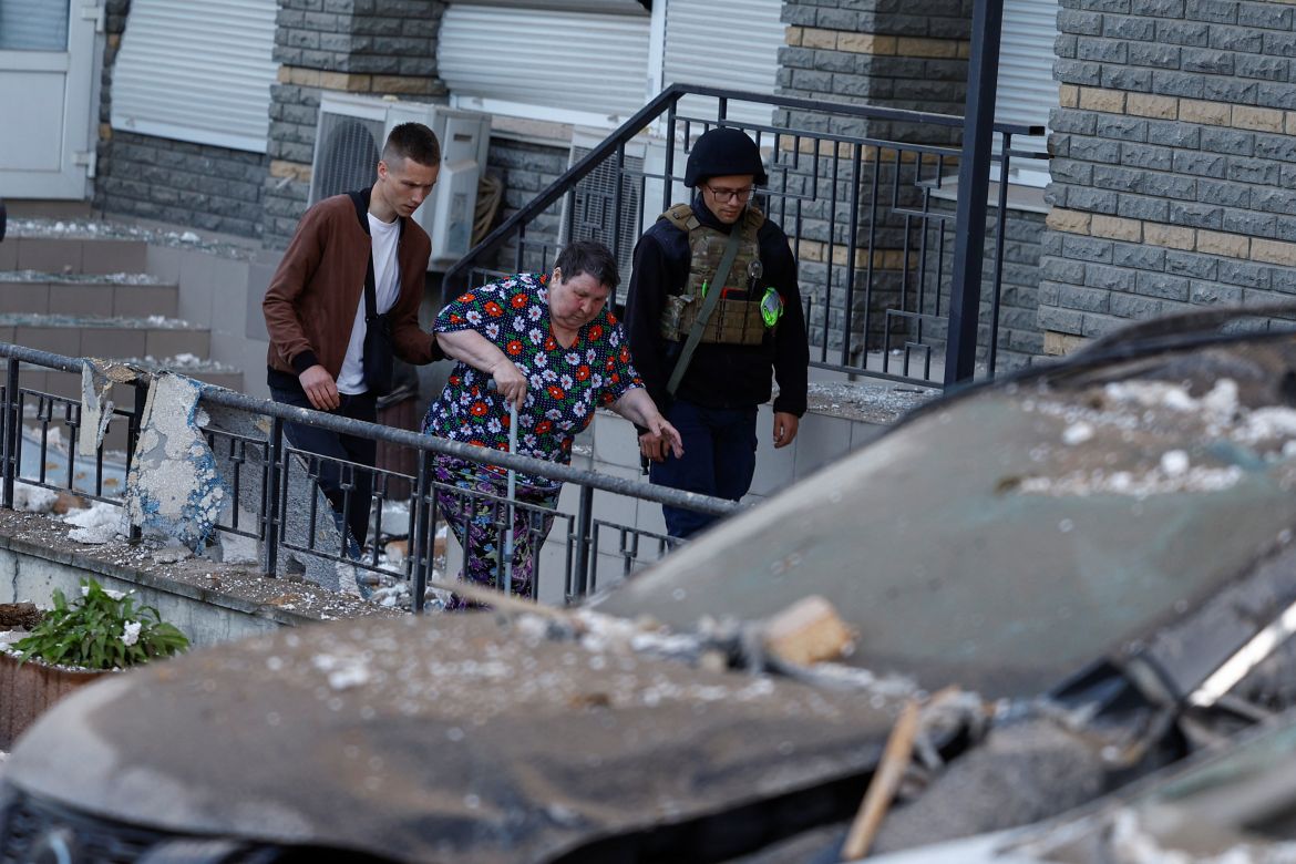 Men helps a woman to be evacuated from an apartment building heavily damaged