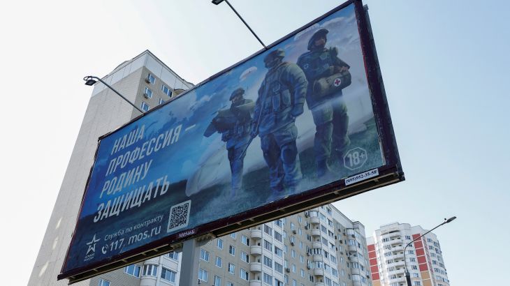An advertising board, which promotes service in the Russian army and invites volunteers to sign a contract with the defence ministry, is on display near a damaged multi-storey apartment block (R) following a reported drone attack in Moscow, Russia, May 30, 2023. A slogan on the board reads: "Our profession is to defend fatherland". REUTERS/Maxim Shemetov