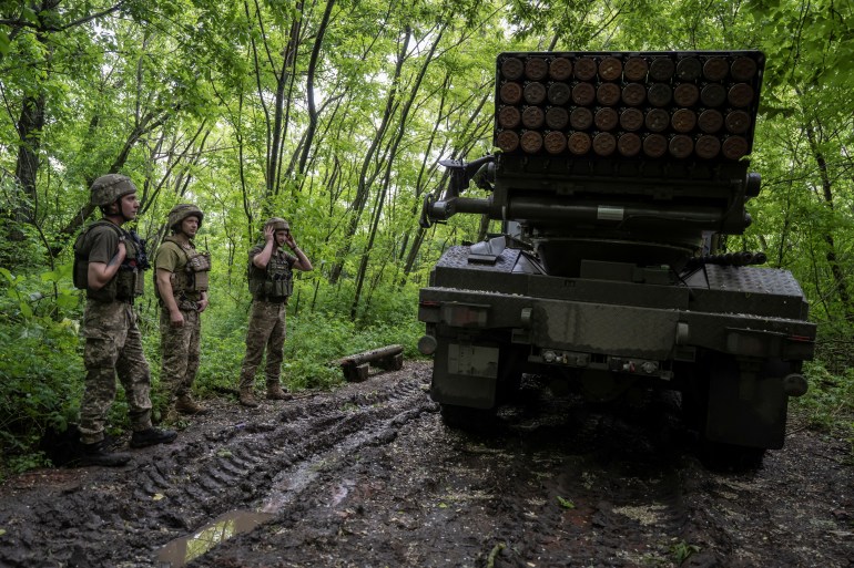 Ukrainian service members of the 55th Separate Artillery Brigade stand next to a Vampire multiple launch rocket system 