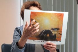 A woman shows pictures drawn of the Hiroshima bombing
