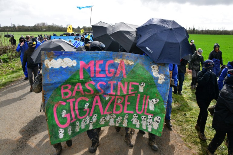 Protesters hold a banner as they arrive for a demonstration called by the collective "Bassines non merci", the environmental movement "Les Soulevements de la Terre" and the French trade union 'Confederation paysanne' to protest against the construction of a new water reserve for agricultural irrigation, in Sainte-Soline, central-western France, on March 25, 2023. - More than 3,000 police officers and gendarmes have been mobilised and 1,500 "activists" are expected to take part in the demonstration, around Sainte-Soline. The new protest against the "bassines", a symbol of tensions over access to water, is taking place under thight surveillance on March 25, 2023 in the Deux-Sevres department. (Photo by pascal lachenaud / AFP)