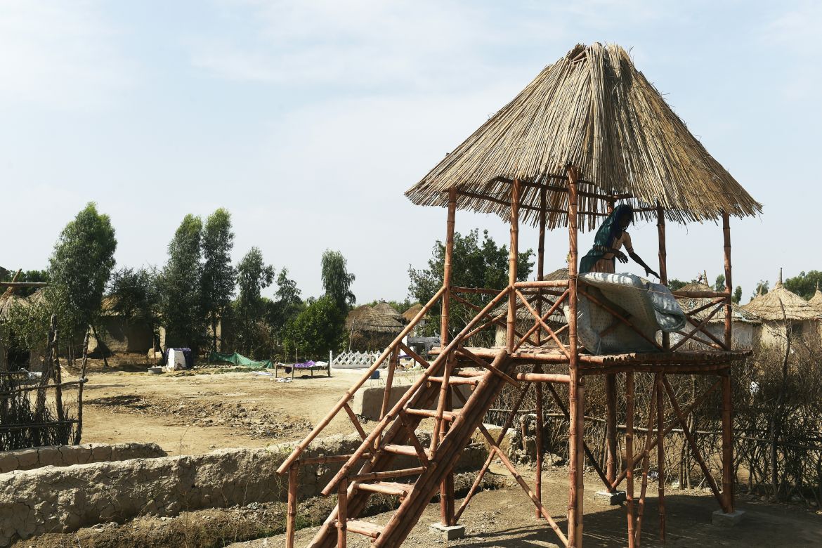 In this picture taken on April 9, 2023, a girl places a mattress for drying at an elevated bamboo structure in Pono Colony at Sanjar Chang village