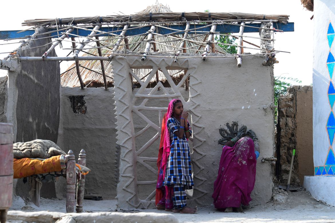 In this picture taken on April 8, 2023, a woman makes a floral ornament on a wall of her under construction flood-resistant hut at Sanjar Chang village