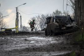A Ukrainian serviceman runs for cover from shelling across a street in the frontline town of Bakhmut, Donetsk region on April 23, 2023, amid the Russian invasion of Ukraine