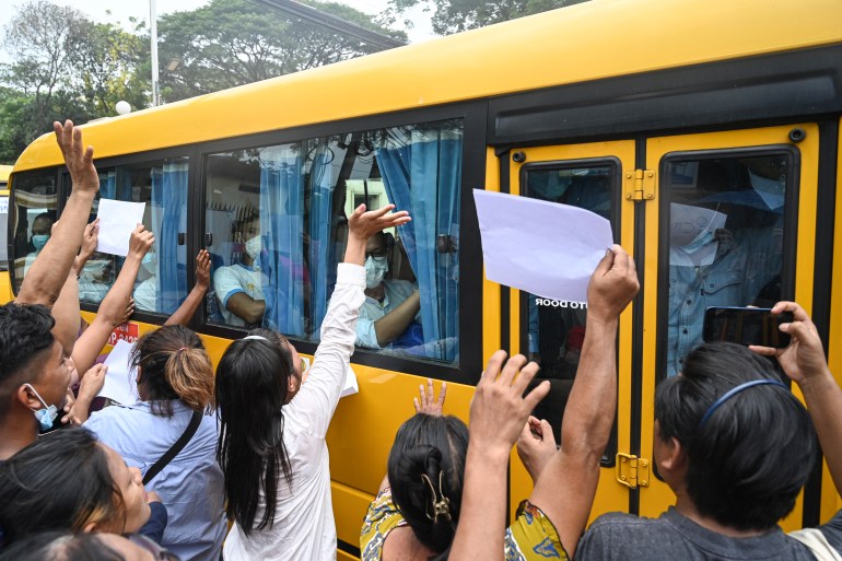 People reach out as a bus carrying pardoned prisoners leaves Insein prison