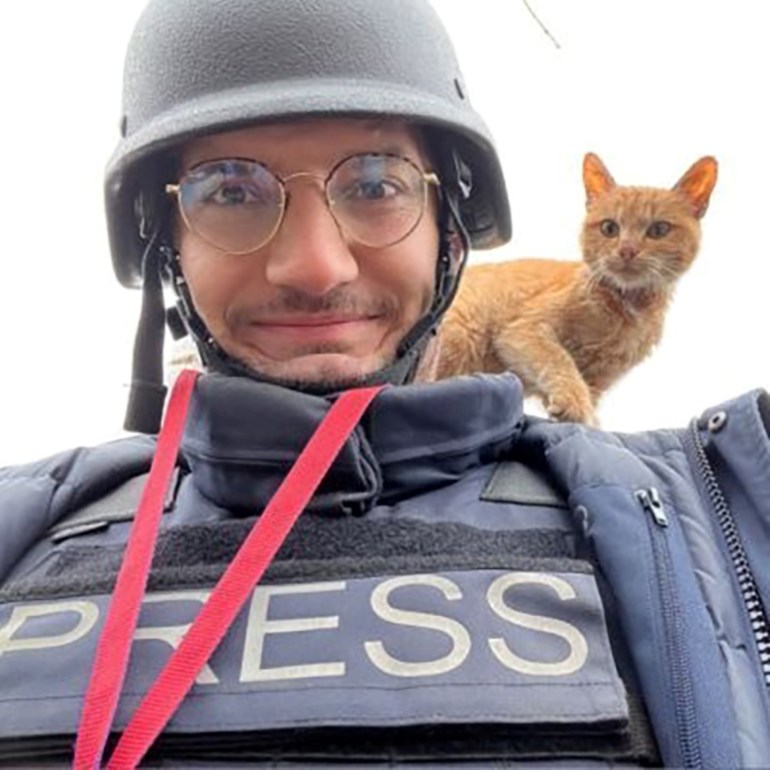 Arman Soldin in a selfie. He is wearing a helmet and body armour and has a ginger cat on his shoulder.
