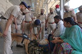 Policemen along with a sniffer dog, checks the belongings of passengers at a railway station in Amritsar
