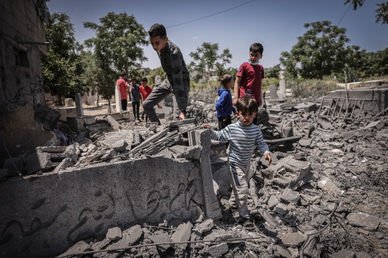 People inspect the damage in a graveyard hit by an Israeli air strike in Beit Lahia in the northern Gaza Strip, on May 13, 2023. - Israeli air strikes battered Gaza again on May 13 in response to rocket fire from militants as deadly fighting resumed after a night of relative calm, despite efforts to secure a truce. (Photo by MOHAMMED ABED / AFP)
