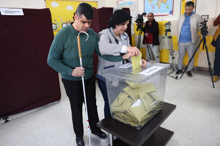 A blind man is assisted as he casts his vote at a polling station in Ankara