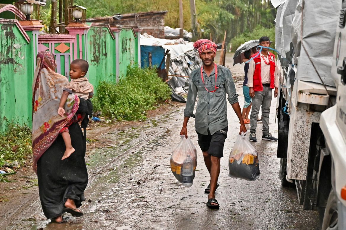A member of Red Crescent Society carries relief material in Teknaf on May 14, 2023, after the cyclone Mocha's landfall. - Cyclone Mocha began to crash ashore at the Bangladesh-Myanmar