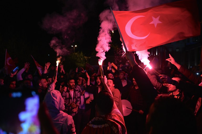 AK party supporters light flares illuminating the red Turkish flag.