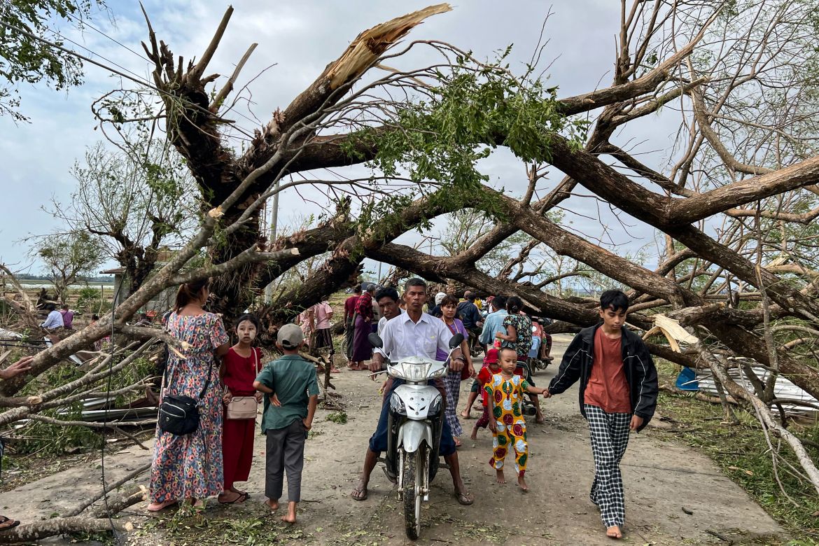 Residents walk past fallen trees in Kyauktaw in Myanmar's Rakhine state
