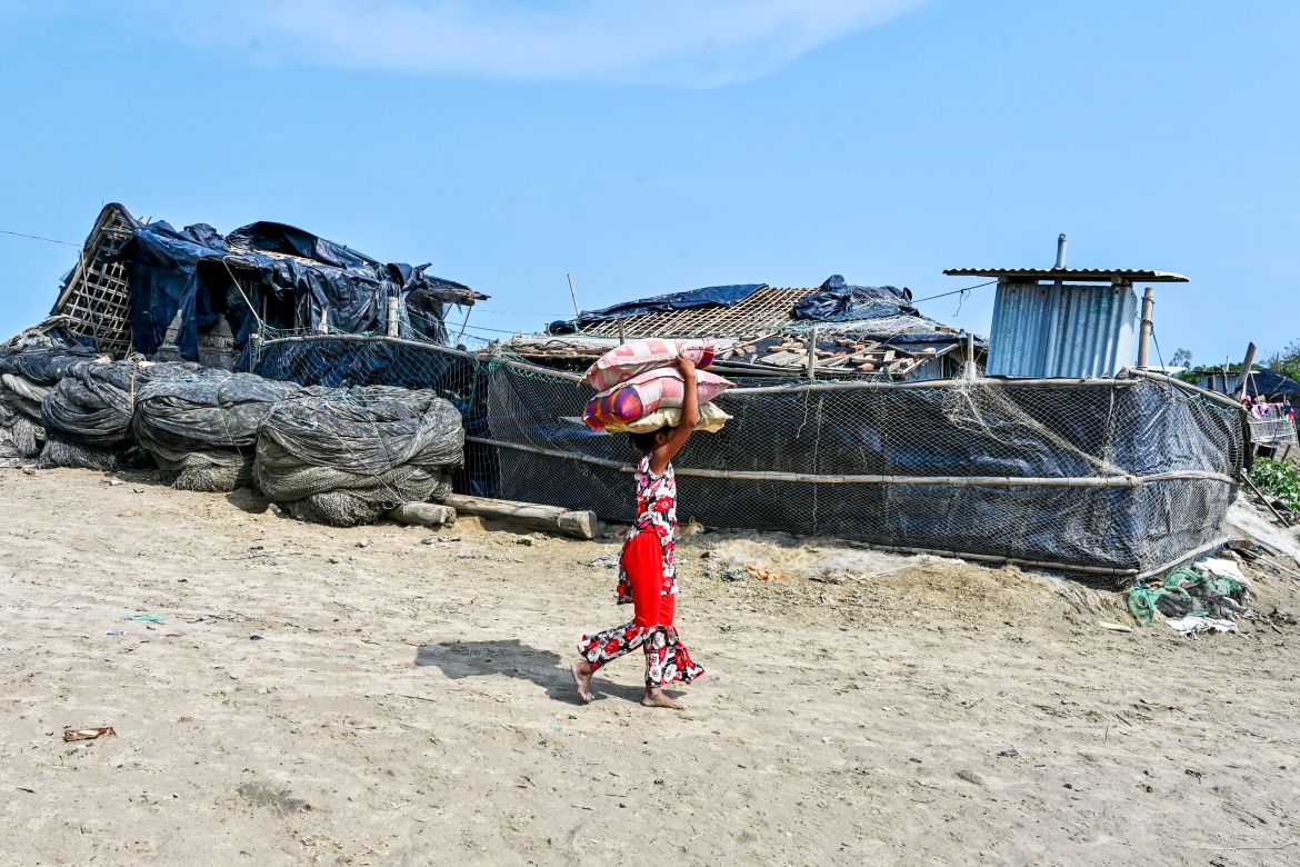 A girl carries belongings as she returns from a shelter in Shahpori island on the outskirts of Teknaf