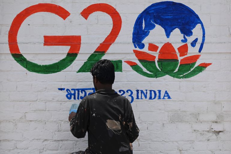 A man paint a wall with the logo of India's G20 summit in Srinagar