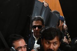 Security personnel with ballistic shields escort former Pakistan's prime minister Imran Khan