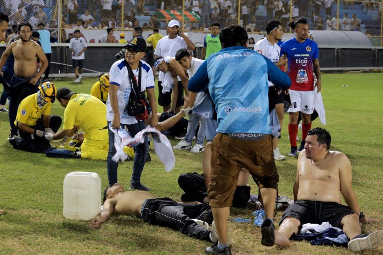 Supporters are helped by others following a stampede during a football match between Alianza and CD FAS at Cuscatlan stadium in San Salvador