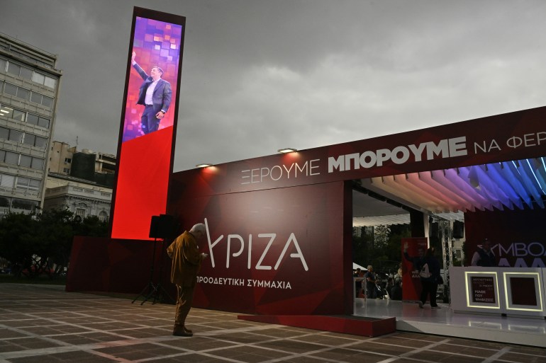 A man stands outside the left-wing Syriza party's campaign kiosk.