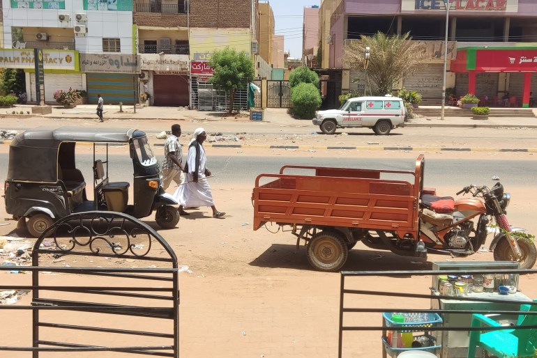 People walk past parked three-wheeled vehicles on al-Sittin (sixty) road in Khartoum