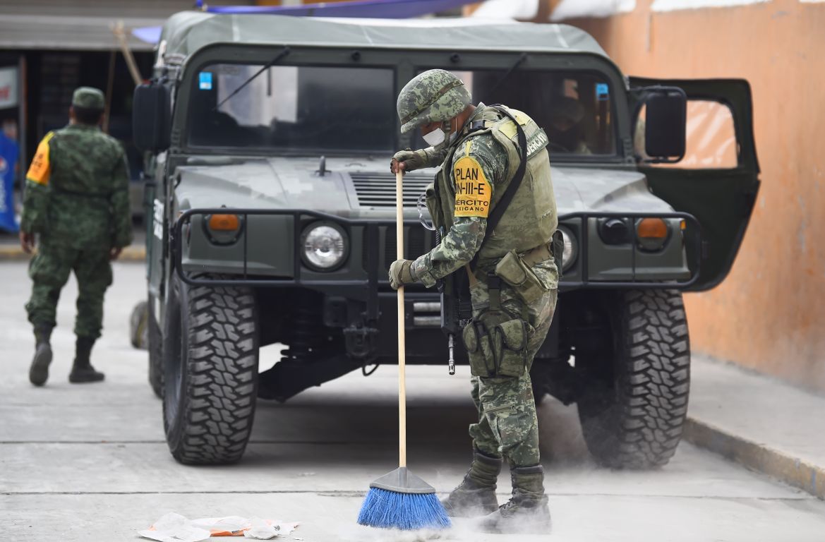 Mexican soldiers sweep the ashes from the streets in the village of Santiago Xalitzintla