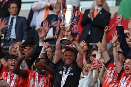 Luton Town&#39;s Welsh manager Rob Edwards lifts the trophy as Luton&#39;s players celebrate after they win the penalty shootout in the English Championship playoff final football match between Coventry City and Luton Town at Wembley Stadium in London on May 27, 2023 [Adrian Dennis/AFP]