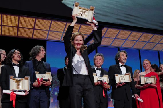 French director Justine Triet (C) celebrates on stage after she won the Palme d'Or for the film "Anatomie d'une Chute" (Anatomy of a Fall) during the closing ceremony of the 76th edition of the Cannes Film Festival in Cannes, southern France, on May 27, 2023. (Photo by Valery HACHE / AFP)