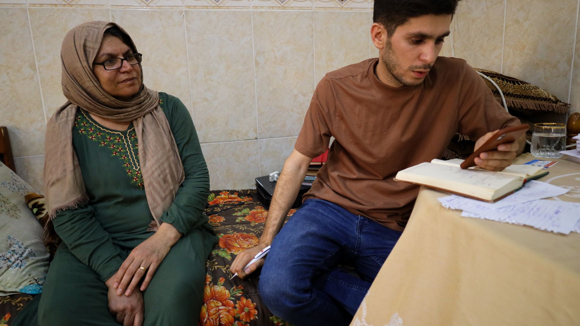 A photo of Mumen and his mother at home in Erbil, looking over April's expenses.