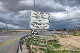 A car drives past a sign for the King Hussein Bridge