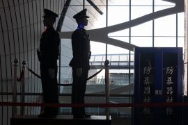 Paramilitary police at the Beijing airport. They are silhouetted against a large window.