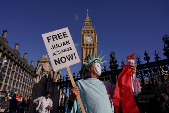 Protesters outside Britain's parliament call for Julian Assange's release. One is dressed as the Statue of Liberty and carrying a placard reading Free Julian Assange Now!