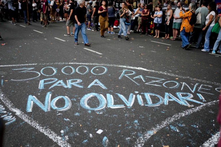 The street is covered by the Spanish phrase "30,000 reasons to not forget" during a march marking the 47th anniversary of the military coup in Buenos Aires, Argentina, Friday, March 24, 2023