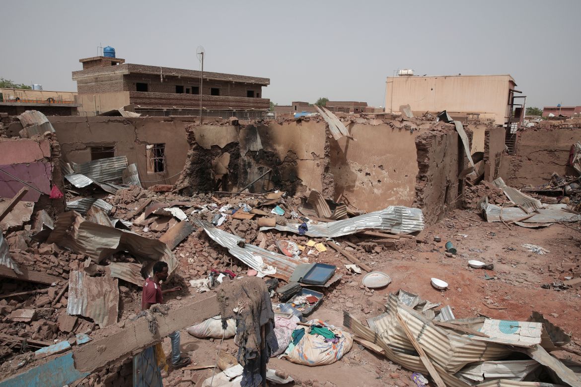 A man walks by a house hit in recent fighting in Khartoum, Sudan