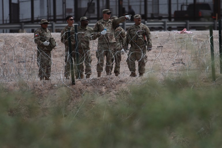 Texas National Guard members install a barbed-wire barrier at the border with Mexico