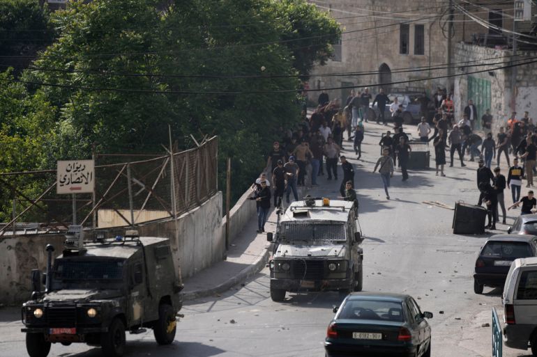 Palestinians chase Israeli military vehicles leaving following an arrest raid, in the West Bank city of Nablus, May 9, 2023